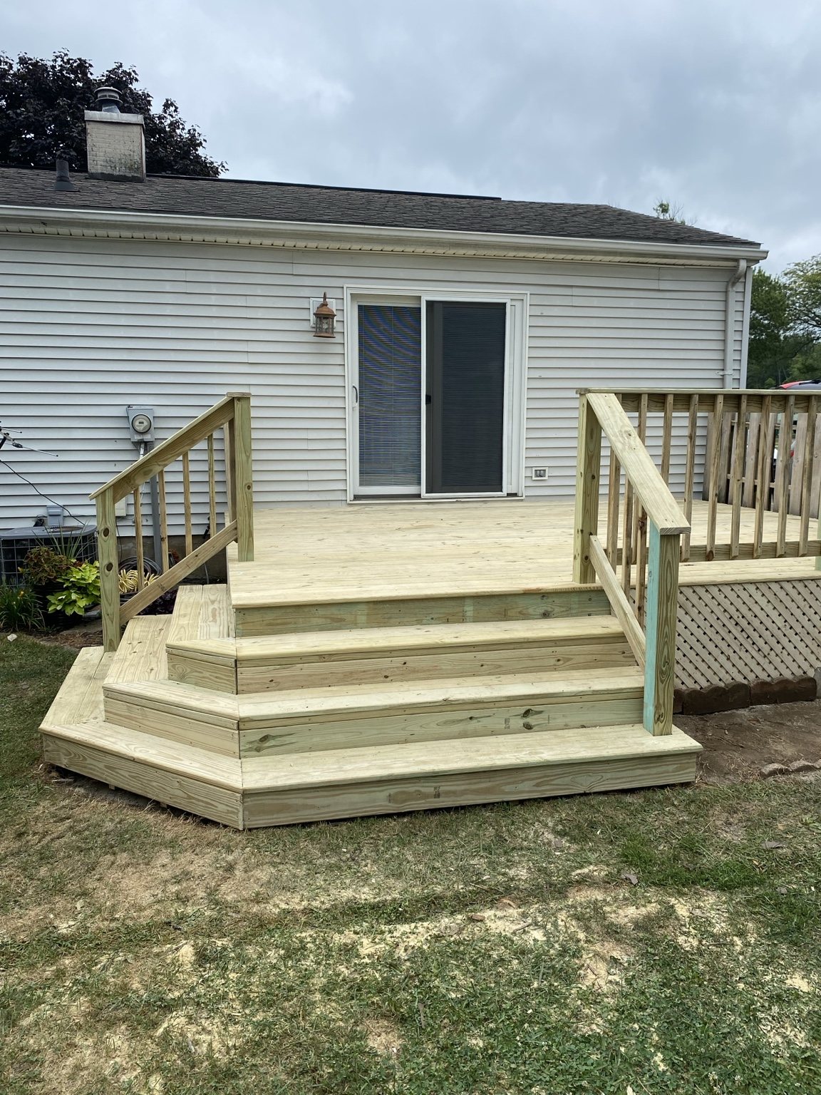 New wood deck and wide steps leading into a backyard