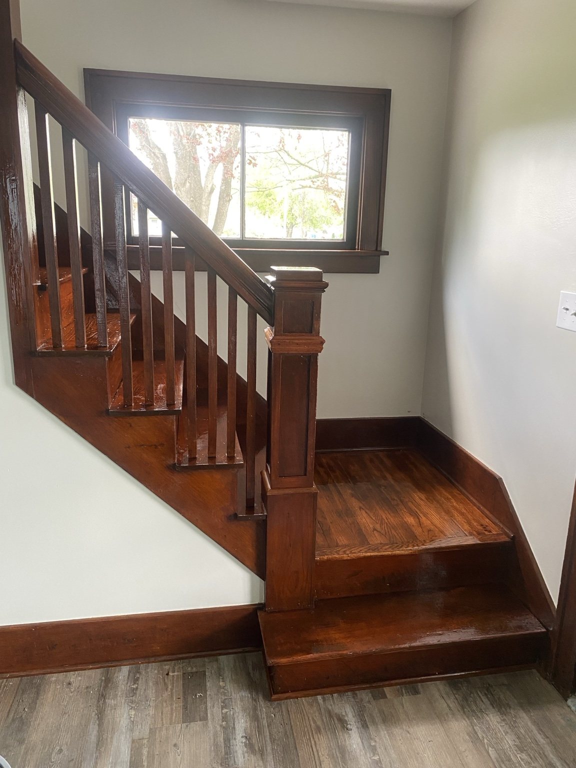Finished wood staircase with railing and bright window
